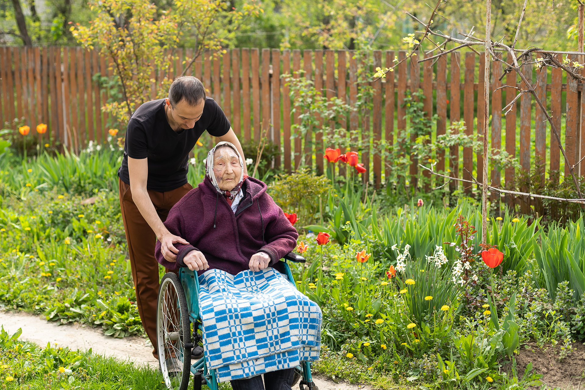 Senior care assistant with very old disabled woman in nursing home