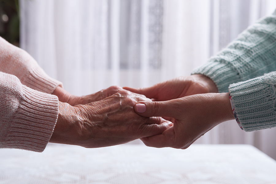 Care is at home of elderly. Senior woman with their caregiver at home. Concept of health care for elderly old people, disabled. Elderly woman holding hands closeup. Space for text white background.